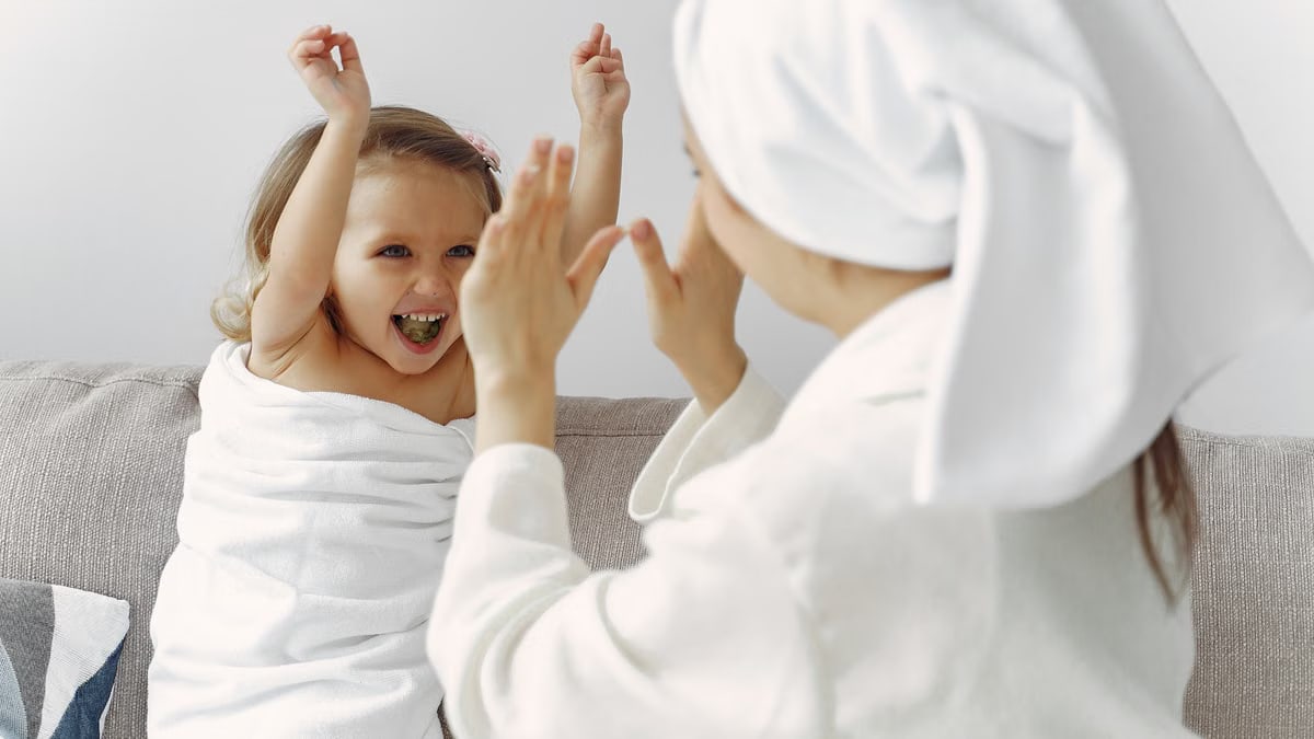 Playful bonding moment between mother and child wrapped in bath towels indoors.